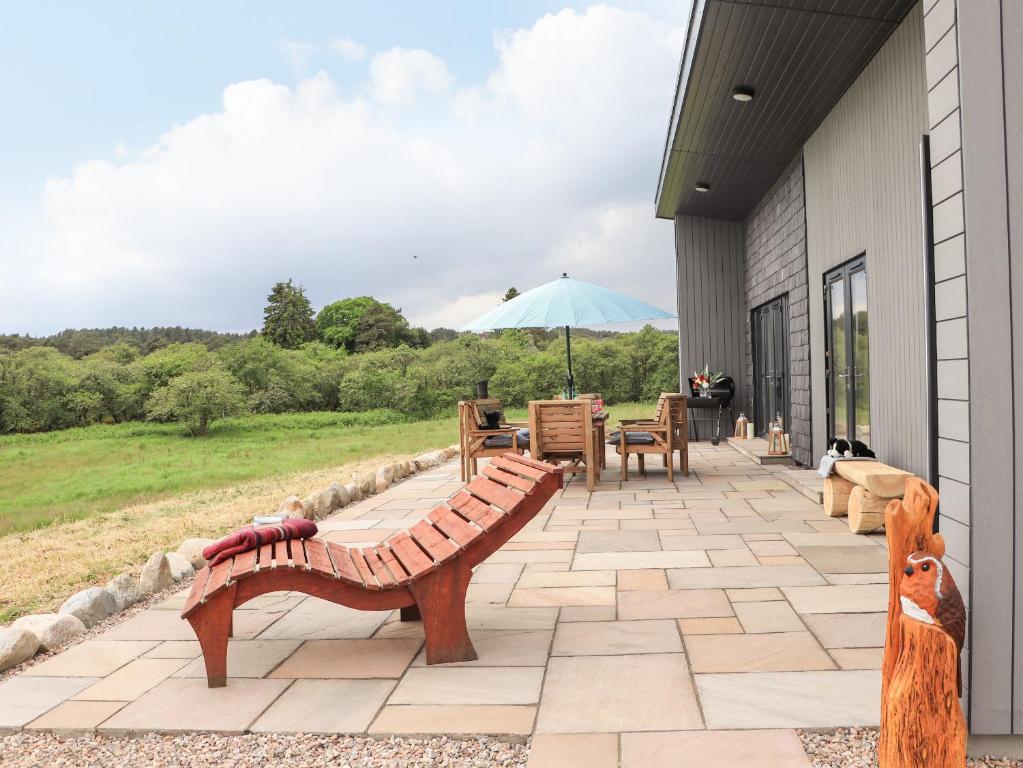 a patio with a bench and a table with an umbrella at Pine Marten in Dornoch