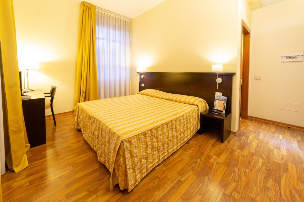 a hotel room with a bed and a wooden floor at Hotel Due Colonne in Cagliari