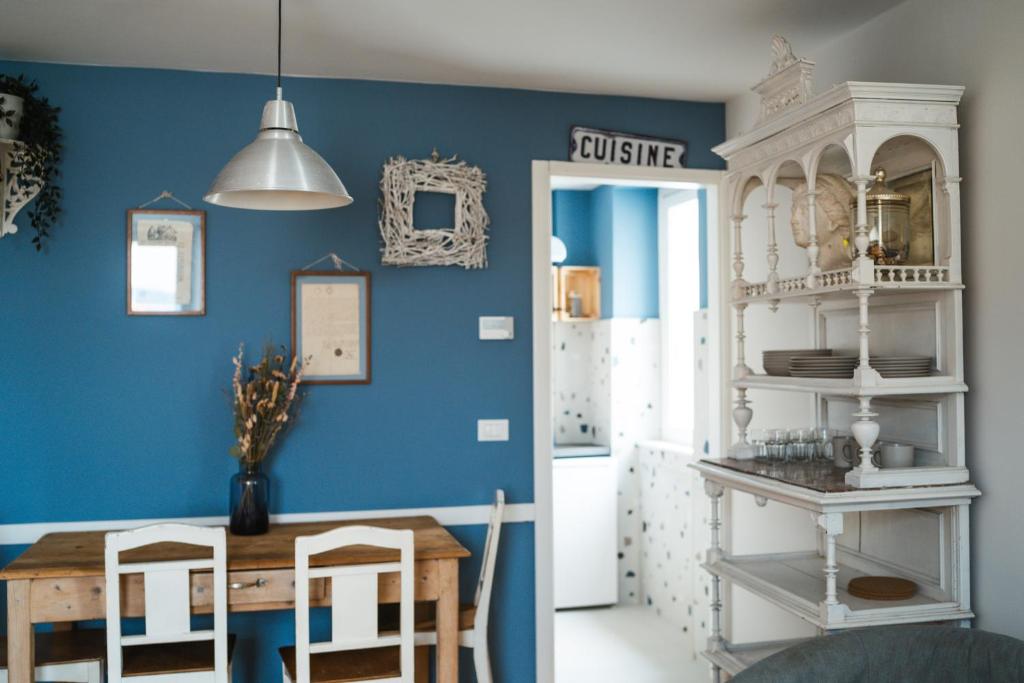 una sala da pranzo con pareti blu e tavolo e sedie di Le Finestre Apartments Muggia a Múggia