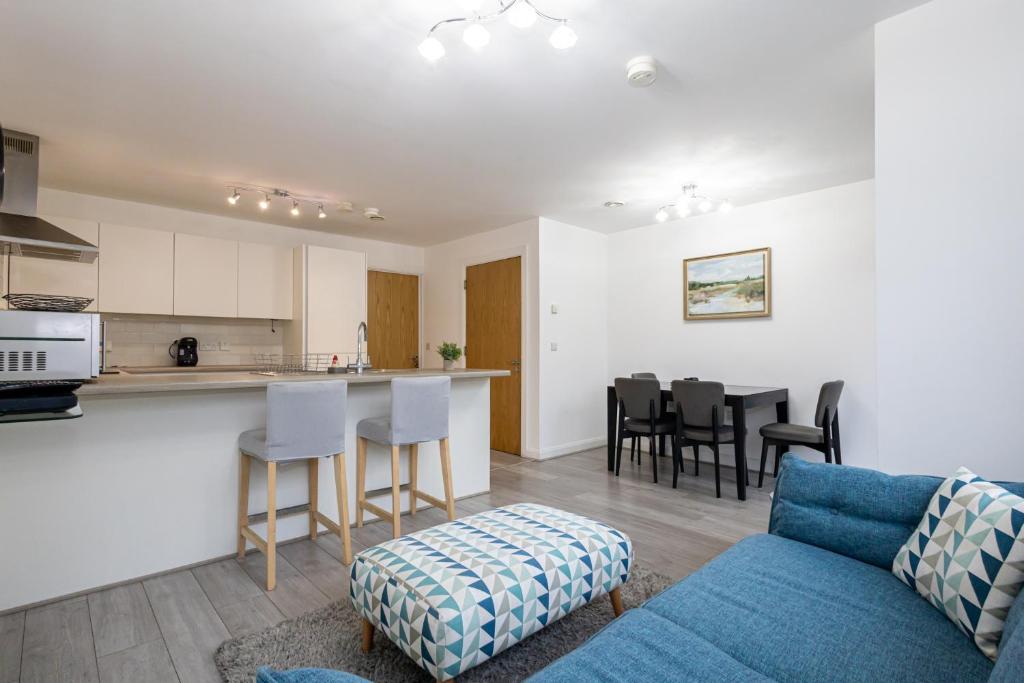 un soggiorno con divano blu e una cucina di Modern 4 Bed Home with Free Parking & Garden a Manchester
