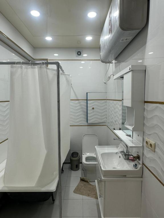 ein weißes Bad mit einem WC und einem Waschbecken in der Unterkunft The Rudaki Home stay in Duschanbe