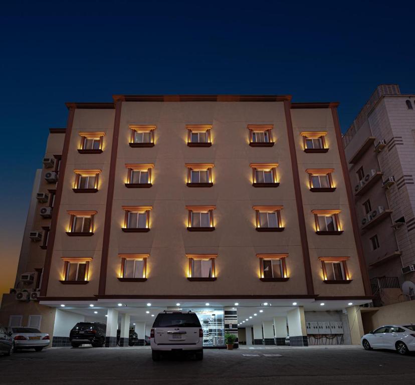 un gran edificio con ventanas iluminadas en un aparcamiento en الياسمين, en Yeda