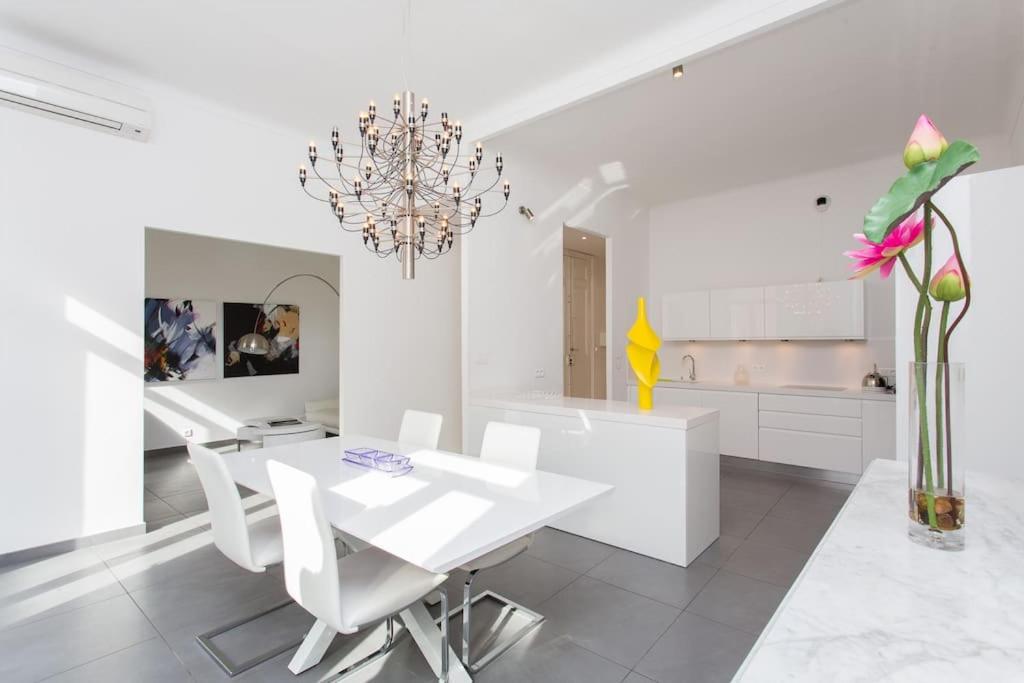 Il comprend une cuisine blanche dotée d'une table à manger et d'un lustre. dans l'établissement 5-Star Apartment on Rue d’Antibes, à Cannes