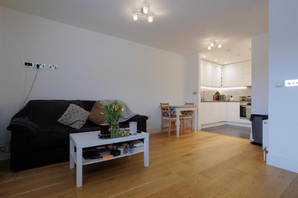 ein Wohnzimmer mit einem schwarzen Sofa und einem Tisch in der Unterkunft Lovely Modern 1-Bed Flat in Kingston in Kingston upon Thames