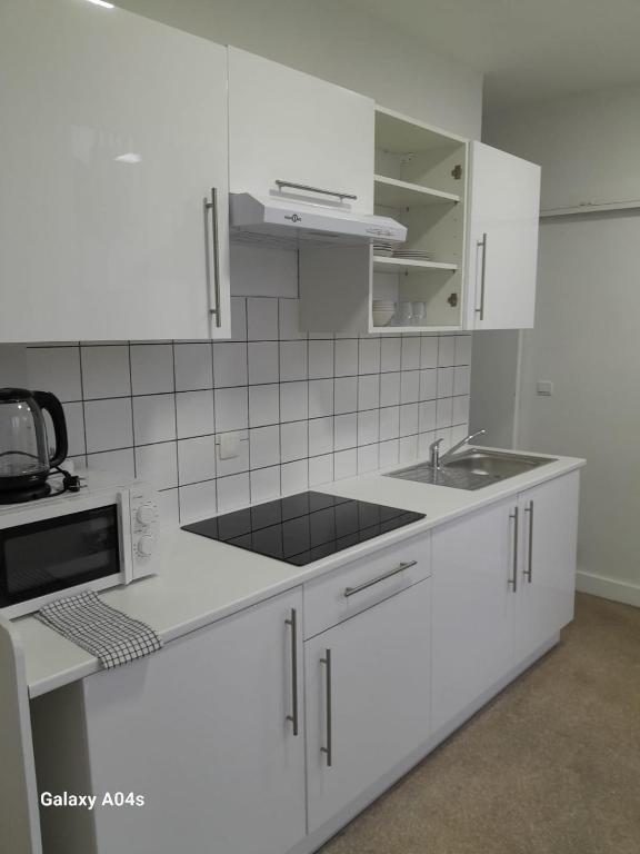 een witte keuken met een wastafel en een magnetron bij The Boulevard Apartment in Brussel