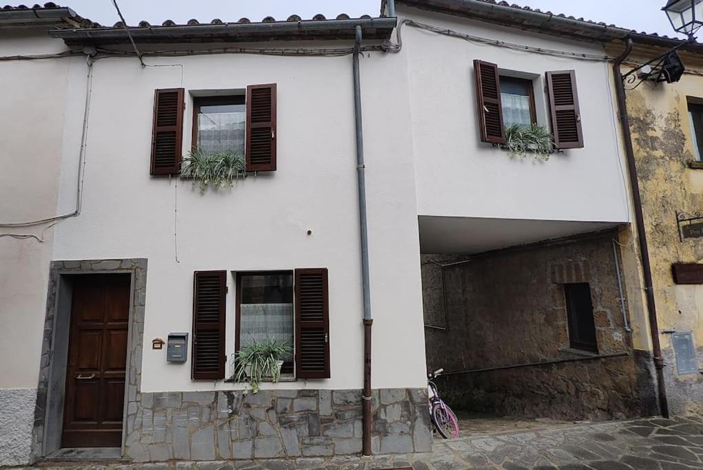 a white house with brown shuttered windows and a garage at La Casetta sotto la Torre in Lubriano