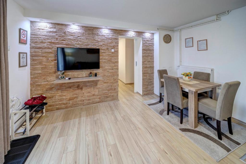 a dining room with a table and a television on a brick wall at Apartman Nena in Pirot