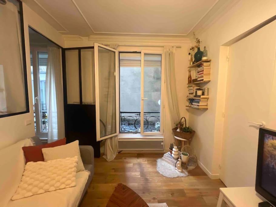 un salon avec un canapé et une fenêtre dans l'établissement 2 PIECES COZY IN THE HEART OF PARIS, à Paris