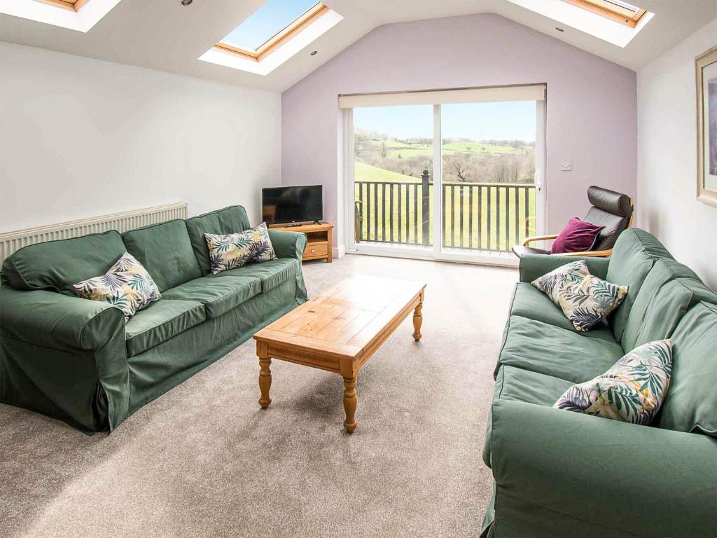 a living room with a green couch and a coffee table at Heather Cottage- Uk45889 in Farlam