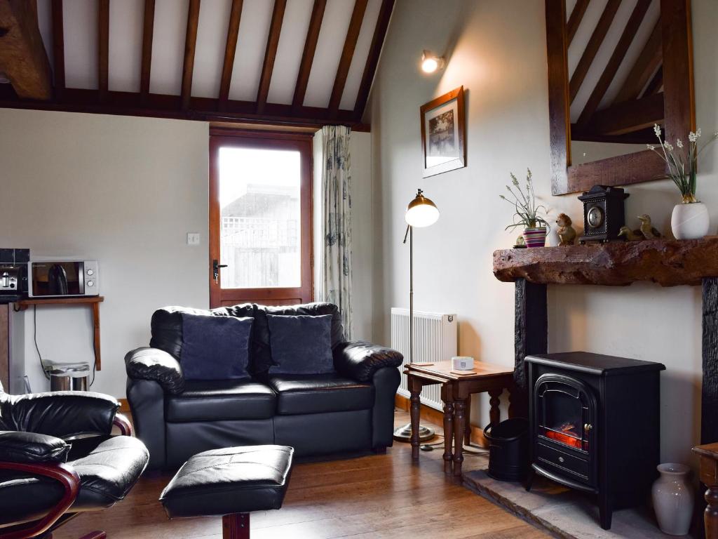 uma sala de estar com um sofá e uma lareira em Byre Cottage - Meadowbrook Farm em Thame