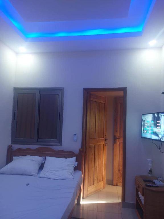 - une chambre dotée d'un lit avec une lumière bleue au plafond dans l'établissement Castor, à Ziguinchor