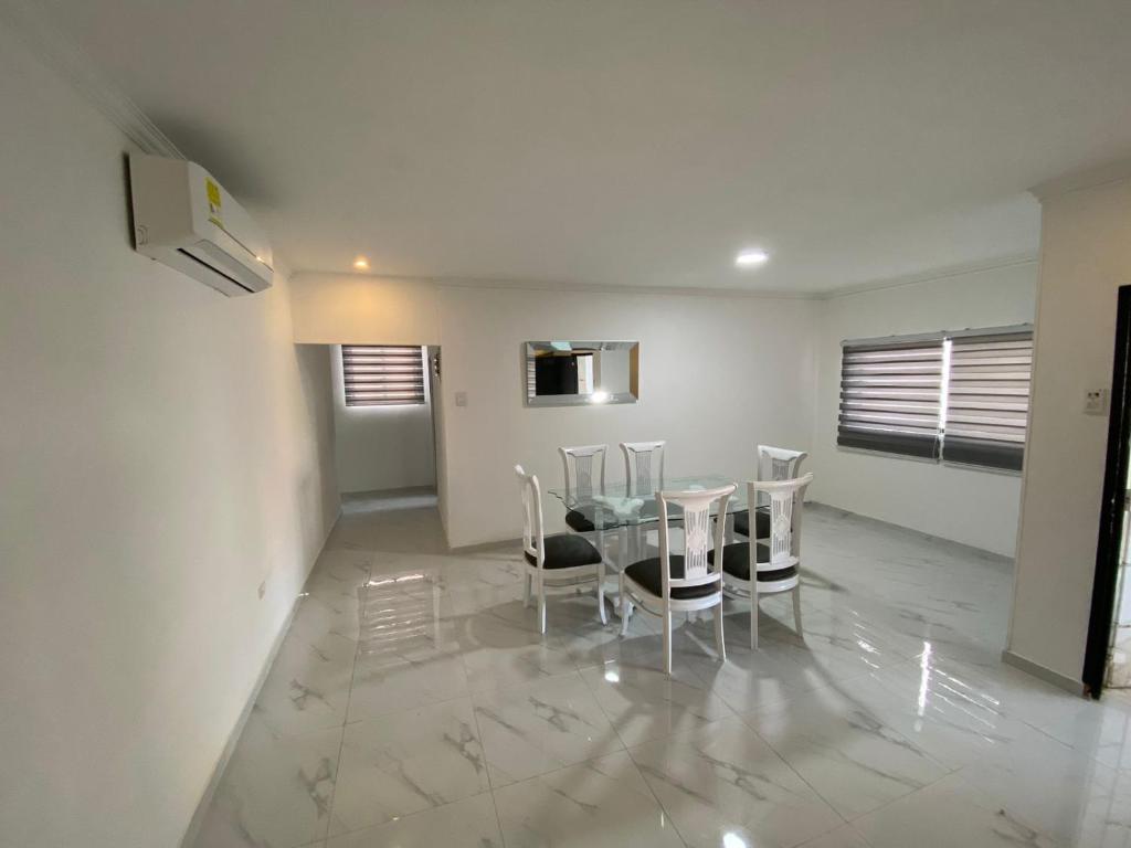 uma sala de jantar com uma mesa de vidro e cadeiras em Apartamento excelente ubicación em Barranquilla