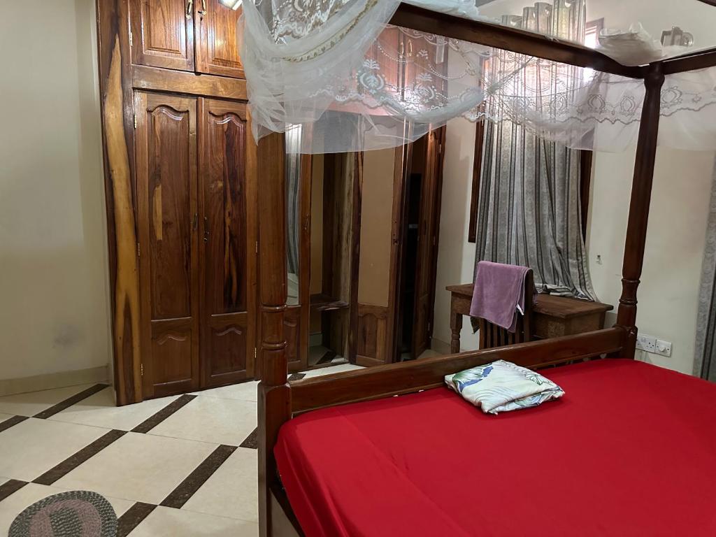 a bedroom with a canopy bed with a red blanket at Pazuri apartment in Ngambo