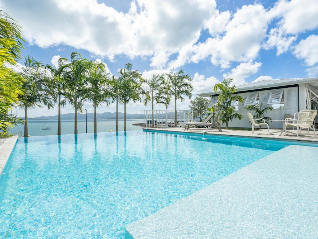 a swimming pool with palm trees and a house at B&B HOTEL Fort-de-France in Fort-de-France