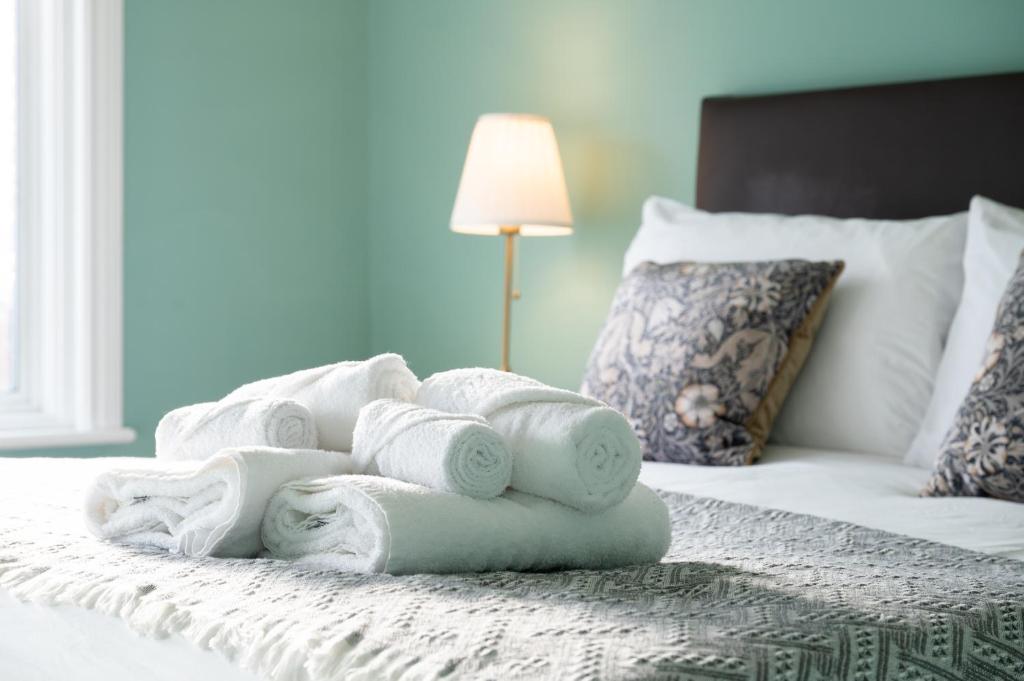 a pile of towels sitting on top of a bed at A Stylish Gem with King Beds - WiFi & Parking in London
