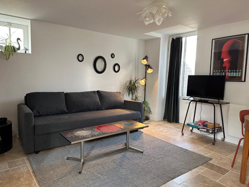 ein Wohnzimmer mit einem Sofa und einem Tisch in der Unterkunft La cour fleurie in Neuville-aux-Bois
