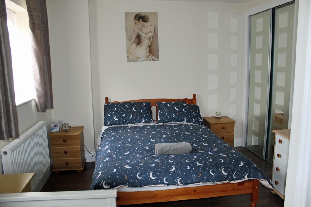 a bedroom with a bed with a blue comforter at Cosy room with 3 bed spaces in a friendly bungalow in Bletchley