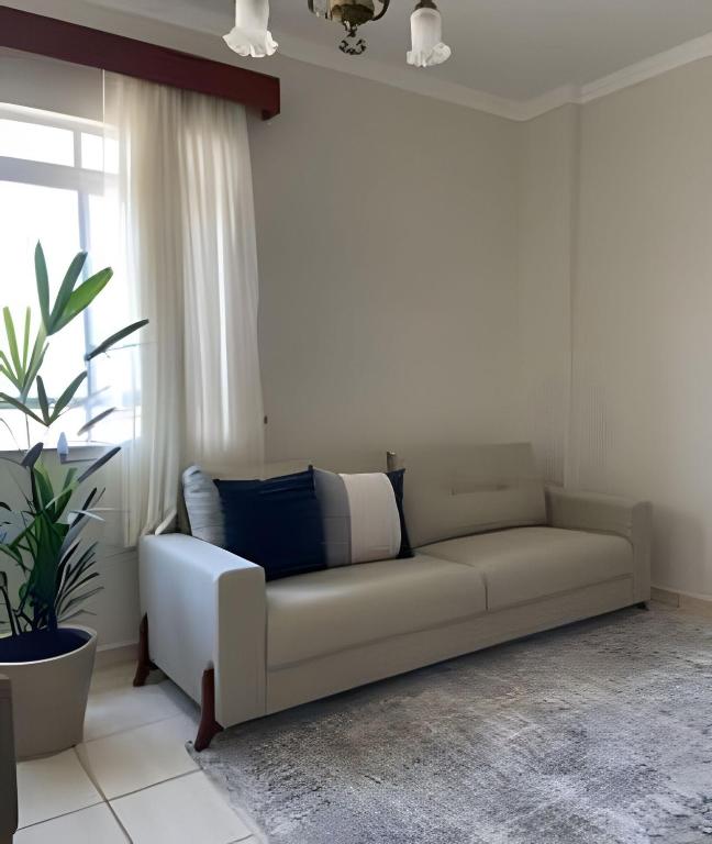 a white couch in a living room with a window at Apartamento no Centro! in Franca