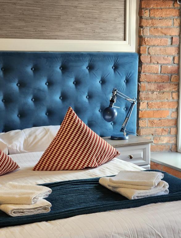 a bed with a blue headboard and a lamp on a table at Maynooth Serviced Studios in Maynooth