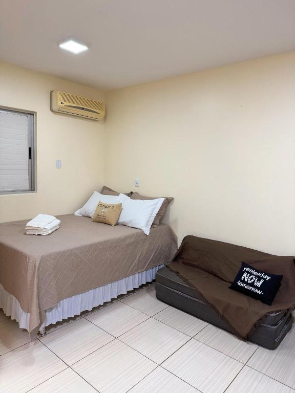 um quarto com uma cama e uma mala no chão em Studio25_Apto região central Foz em Foz do Iguaçu