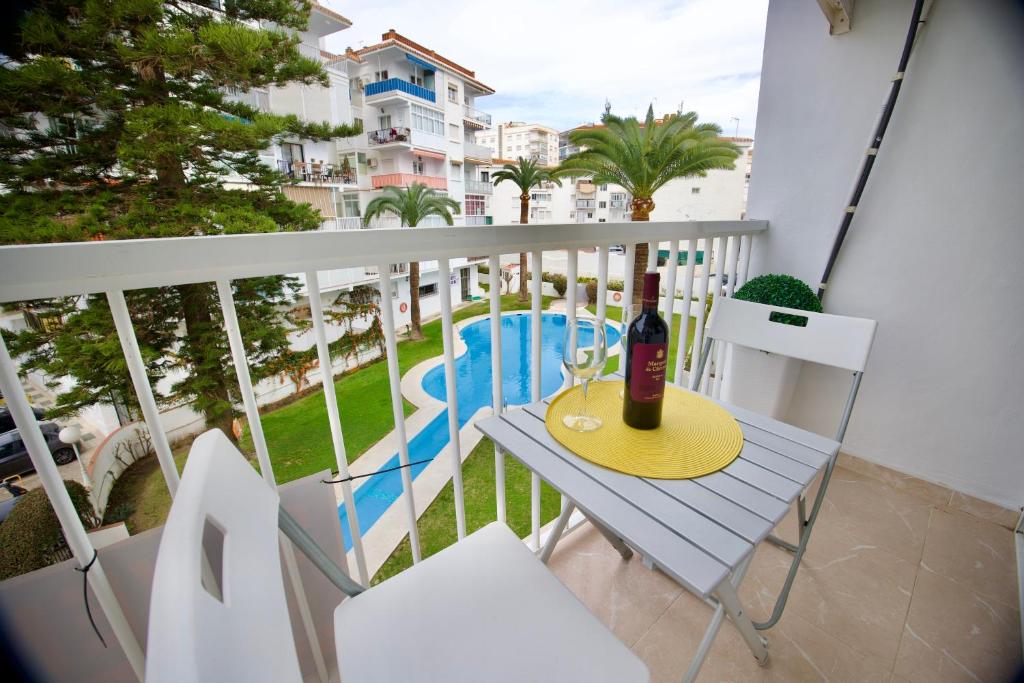 Una botella de vino en una mesa en un balcón en Complejo Andalucía Torrecilla Beach, en Nerja