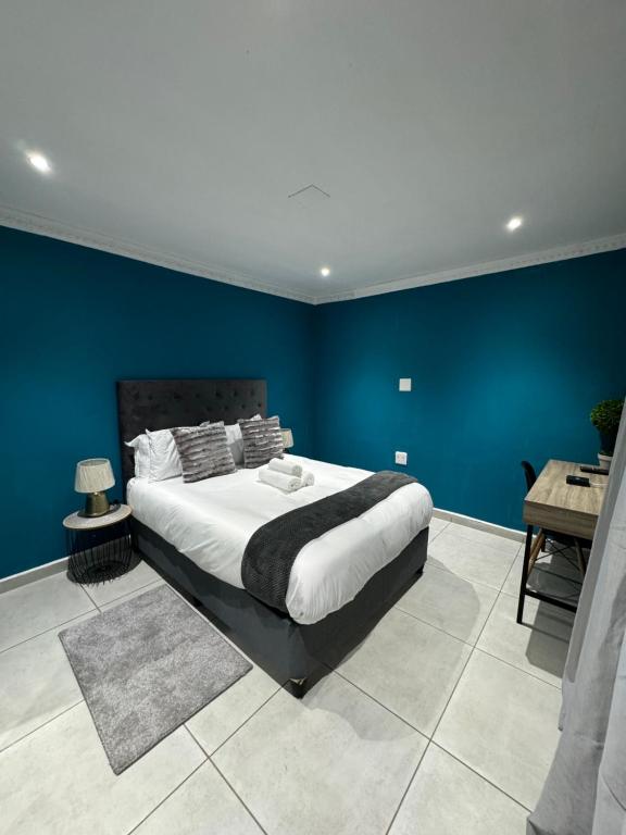 1 dormitorio con 1 cama grande y pared azul en Entindini guest house en Empangeni