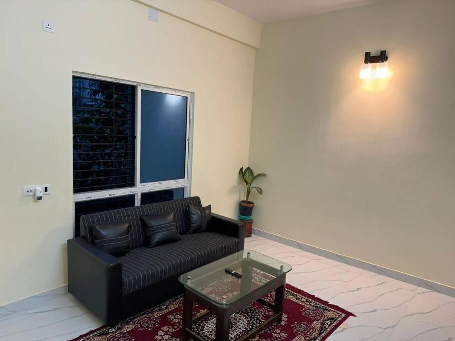 - un salon avec un canapé noir et une fenêtre dans l'établissement Chawali Family Home, à kolkata