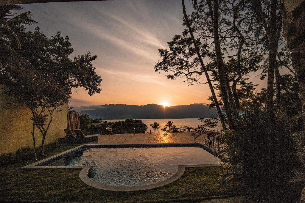 a swimming pool with a sunset in the background at suites vista pro mar ilhabela in Ilhabela