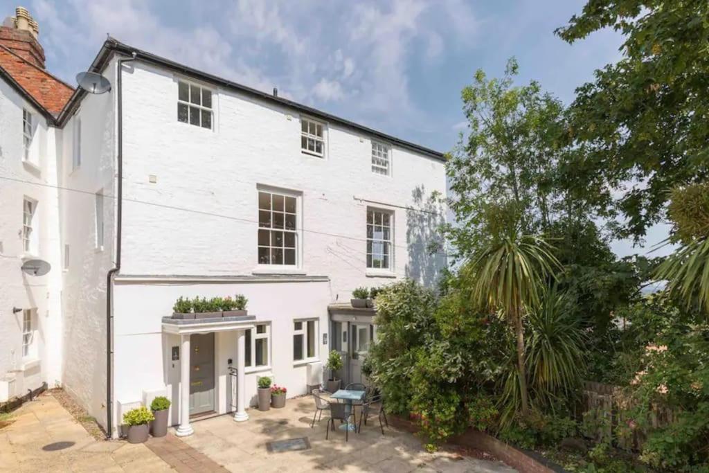 an exterior view of a white house with a patio at Fabulous ground floor apartment. in Great Malvern