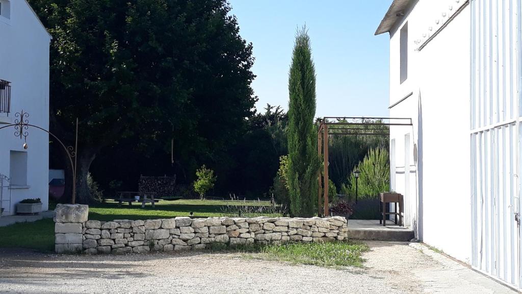 un mur en pierre devant un bâtiment blanc dans l'établissement Mas de l espine, à Eygalières