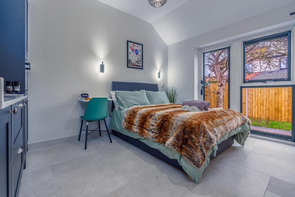 a bedroom with a bed and a table and two windows at Modern studio w/ underfloor heating & parking in Bristol