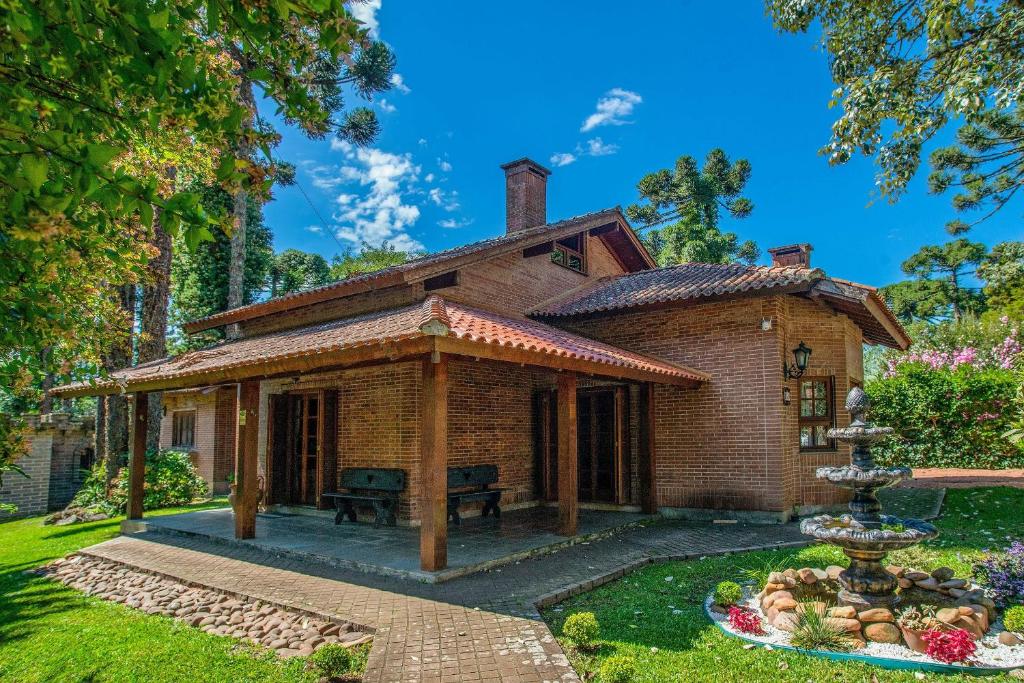 ein altes Backsteinhaus mit einem Brunnen im Hof in der Unterkunft Bela casa estilo chalé em Canela RCF160 in Canela