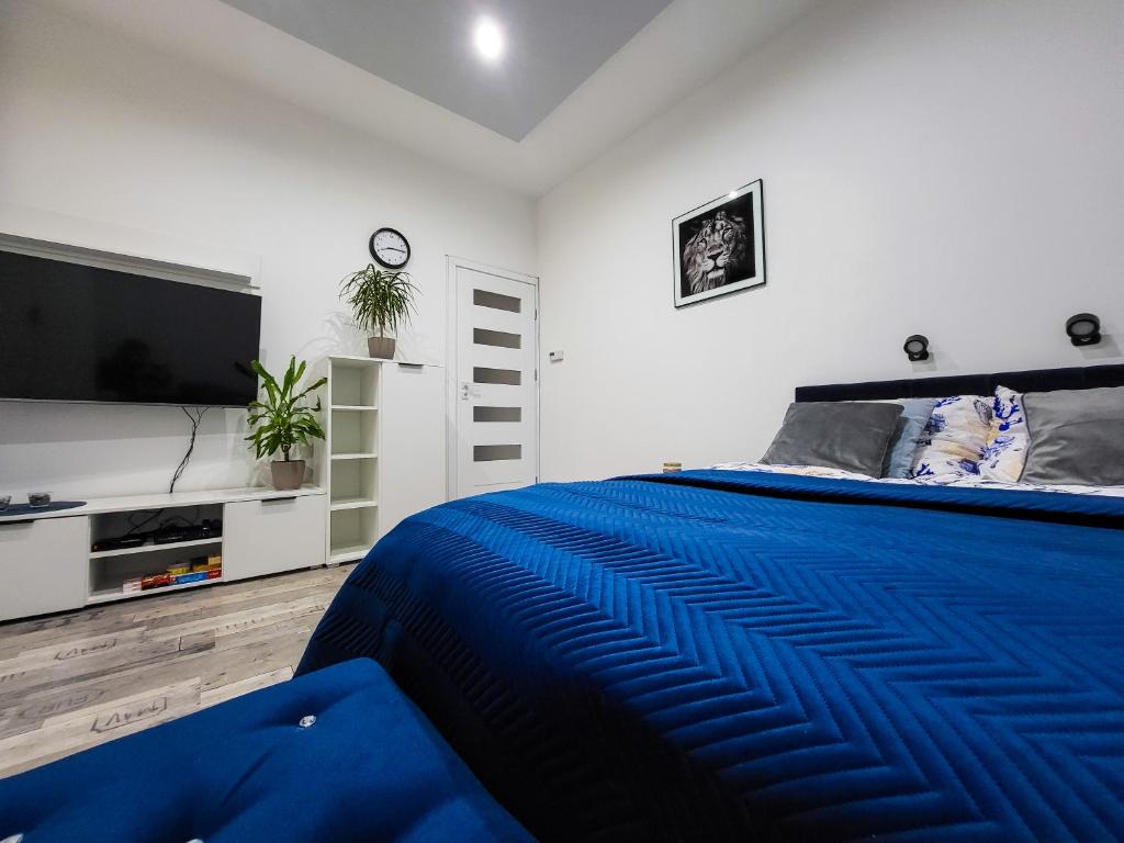 a bedroom with a blue bed and a flat screen tv at Apartament Sea&Forest in Międzyzdroje