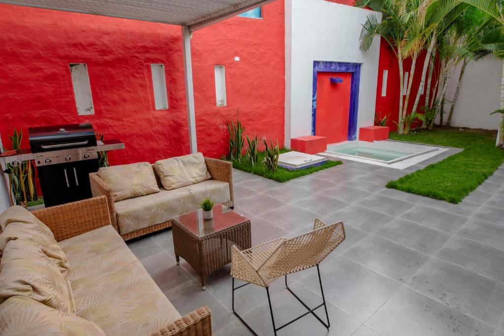 Hotel Casa David في ريفيرا: فناء مع أريكة وكراسي وجدار احمر