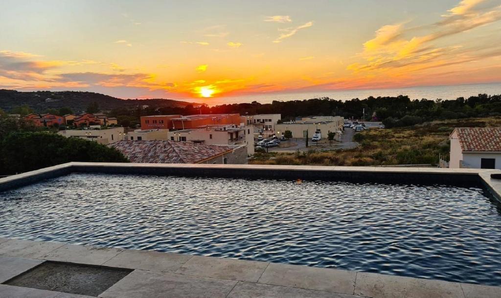 a swimming pool with a sunset in the background at Villa avec piscine et vue mer à Lozari in Palasca