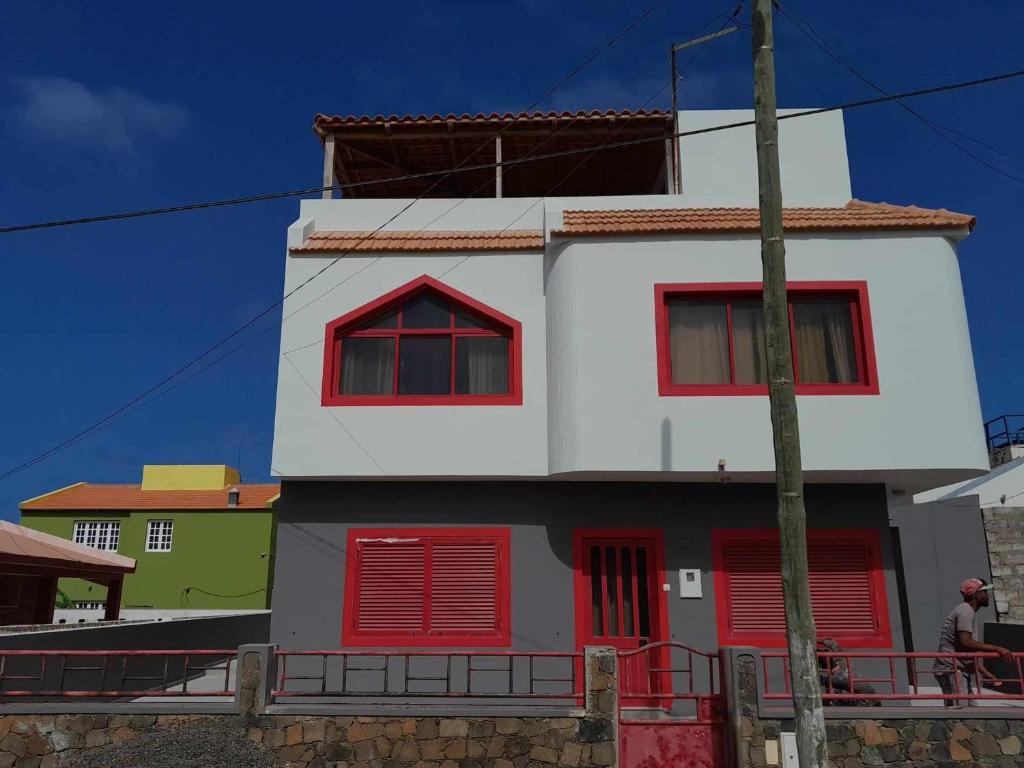 un edificio blanco y rojo con ventanas de contraventanas rojas en Vivenda Na Baia das Gatas, en Baia das Gatas