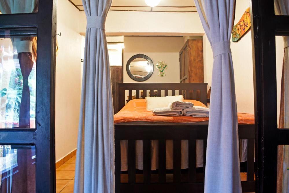 1 dormitorio con 1 cama con cortinas azules y espejo en Hostal Santa Clara B&B, en Apaneca