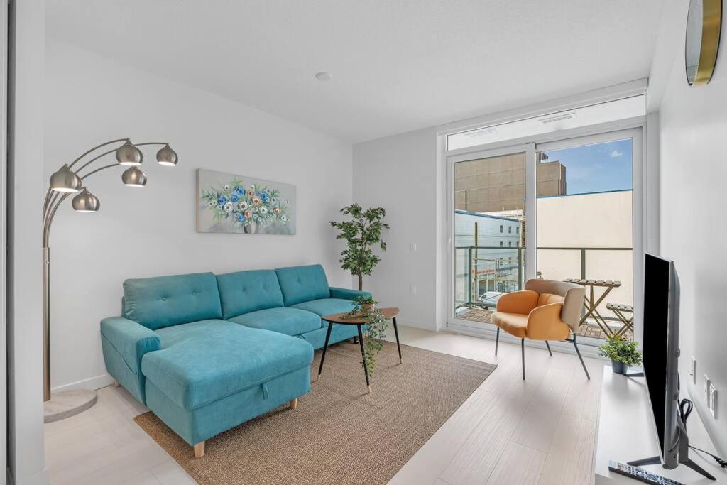 sala de estar con sofá azul y mesa en Modern Apt Near Downtown with Parking, AC & GYM en Vancouver