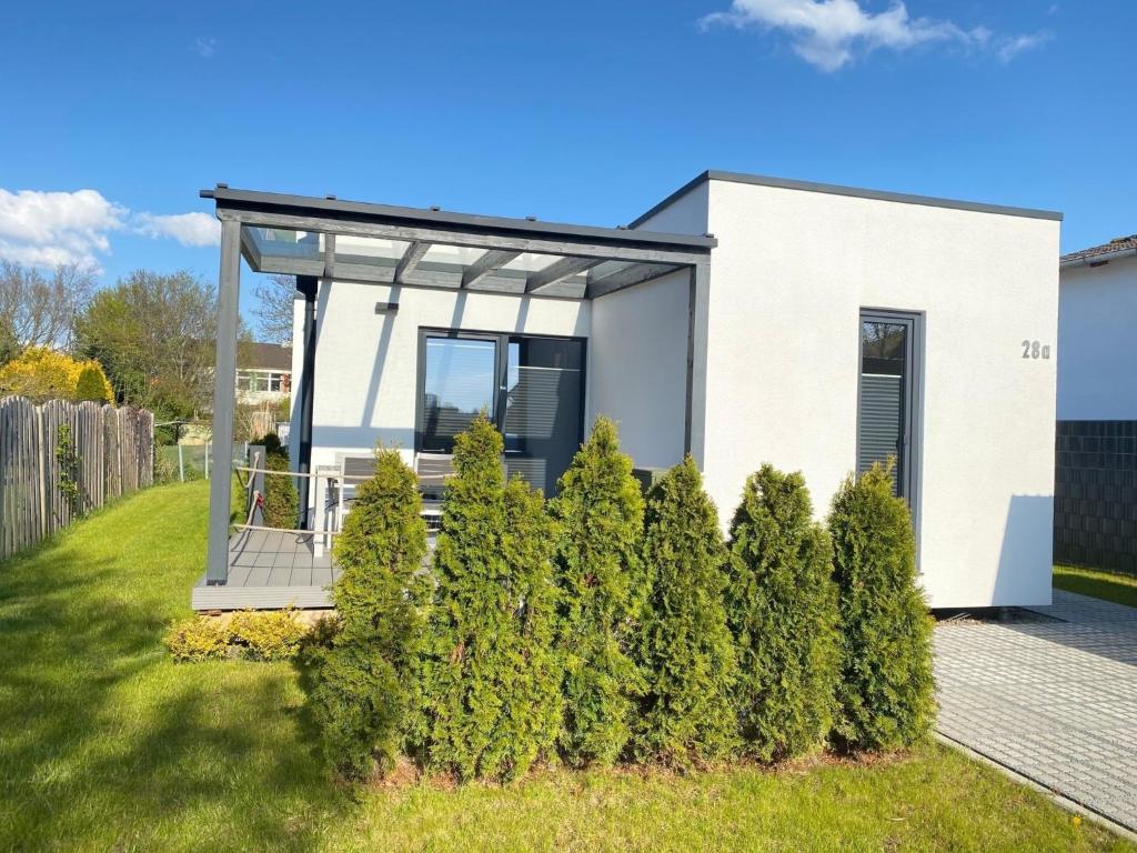 une petite maison blanche avec des arbres devant elle dans l'établissement Ökohaus Spaden, à Schiffdorf