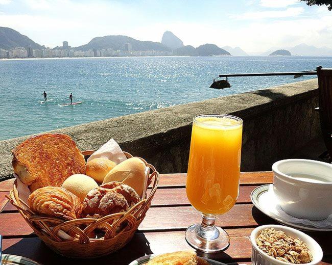 una mesa con una cesta de pan y un vaso de zumo de naranja en Apartamento Copa Surf HIR 8, en Río de Janeiro