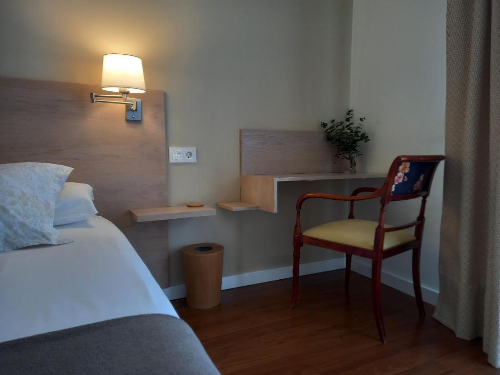 サラマンカにあるLittore Tormes Alojamiento, Parking gratis y Piscinaのベッドルーム1室(ベッド1台、椅子、ランプ付)