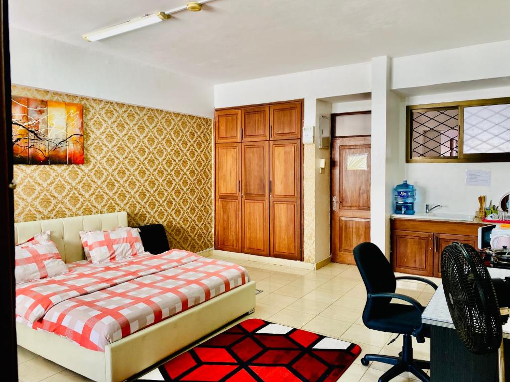 a bedroom with a bed and a desk and a kitchen at Cliff’s Apartment in Dar es Salaam