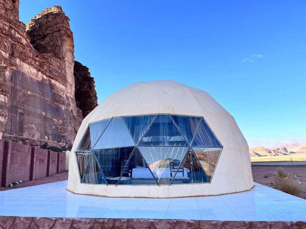 a dome house in the desert with a large window at Rum luxury star in Wadi Rum