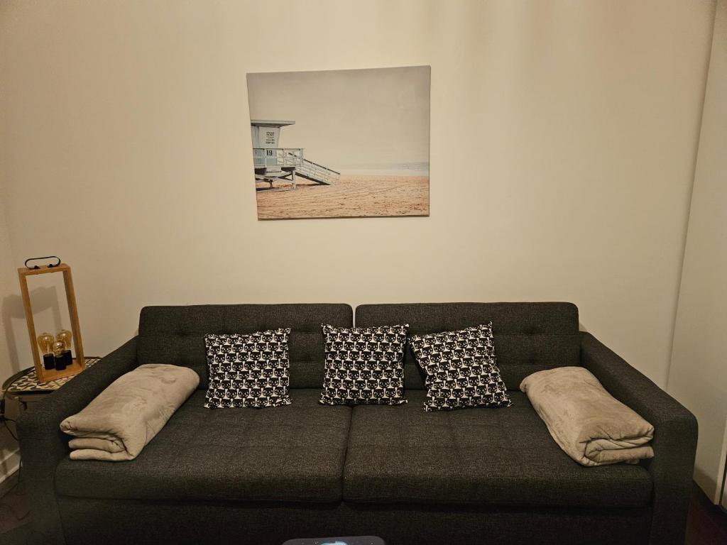 a couch with pillows and a picture of a beach at studio 11 Garcia stade de France in Saint-Denis