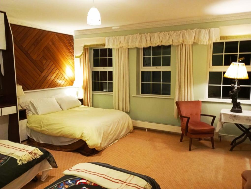 a bedroom with a bed and a desk and two windows at Kiltubber House in Kinnegad