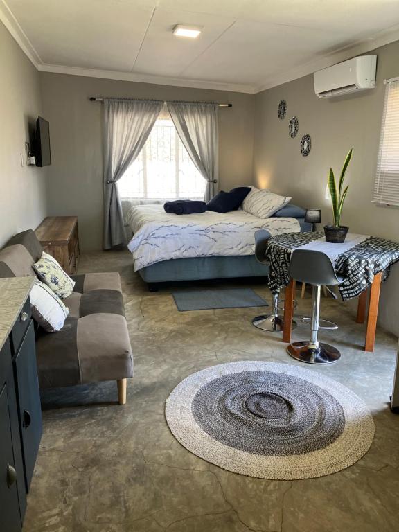 a bedroom with a bed and a couch and a table at Stellies Accommodation - Room 1 in Keetmanshoop