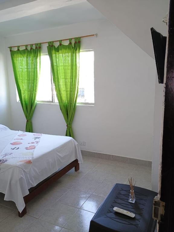 a bedroom with a bed with green curtains and a table at Alojamiento in Bahía Solano