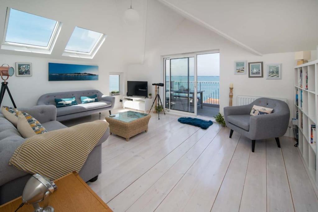 een woonkamer met een bank en stoelen en een televisie bij Solent View, 3bed apartment, fantastic sea views in West Cowes