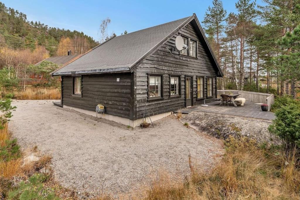 a large wooden house with a patio in front of it at Koselig hytte nær alpinbakke in Åseral