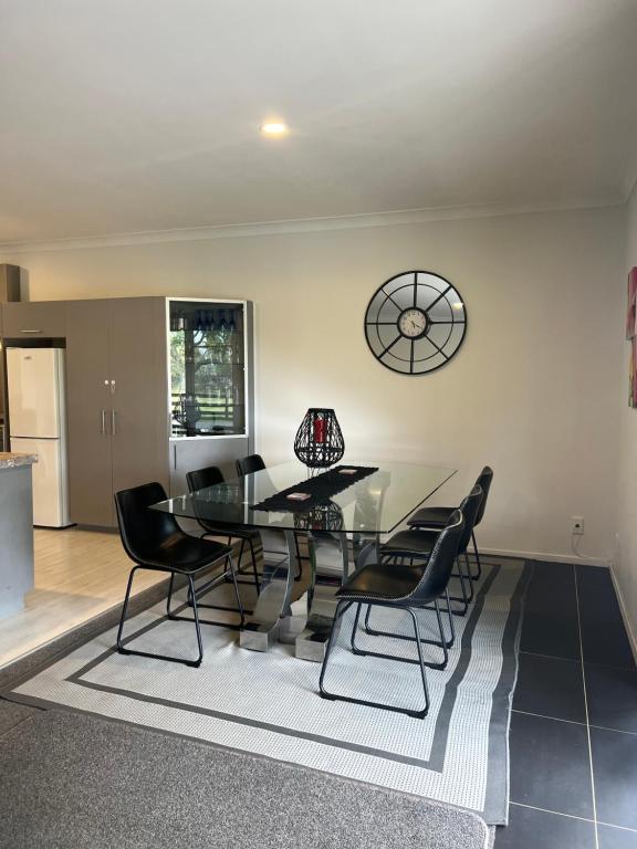 a dining room with a glass table and black chairs at A Cut Above Lodge - The Gateway to the Bay of Islands in Kerikeri